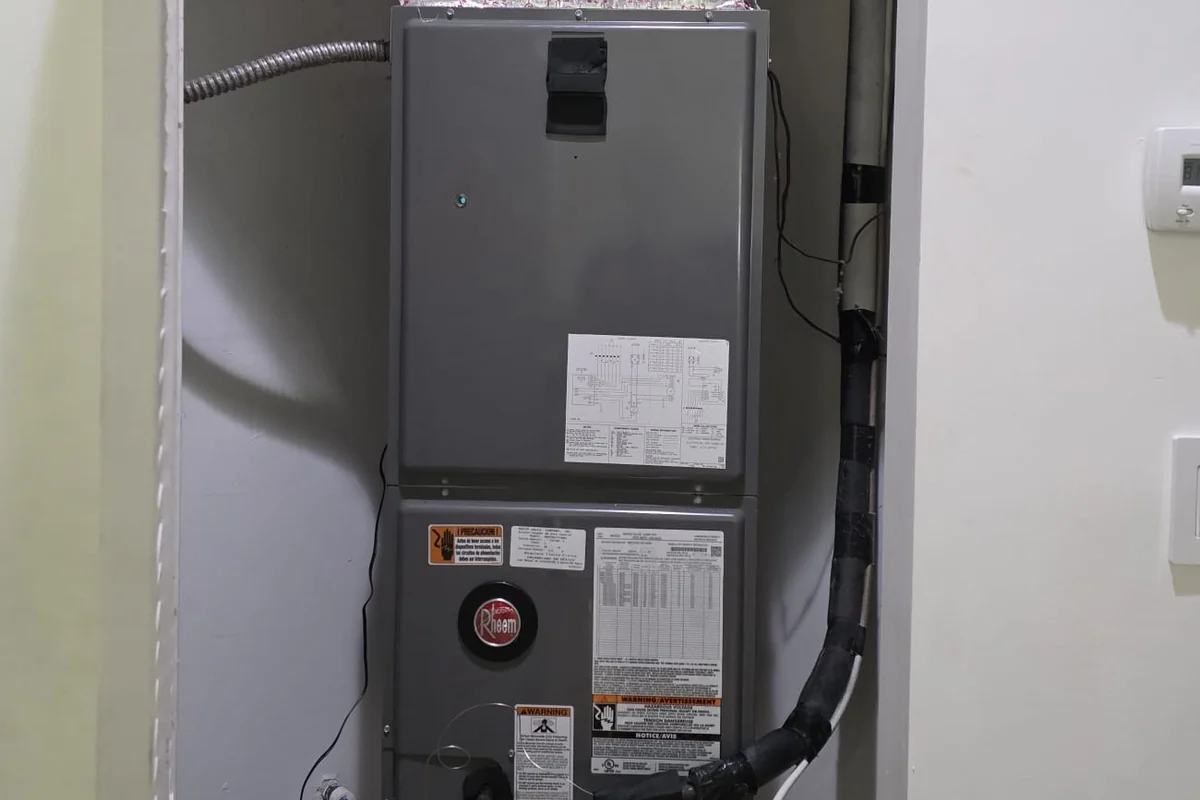 Indoor air handler cabinet in a closet with refrigerant lines and a drain line running from it