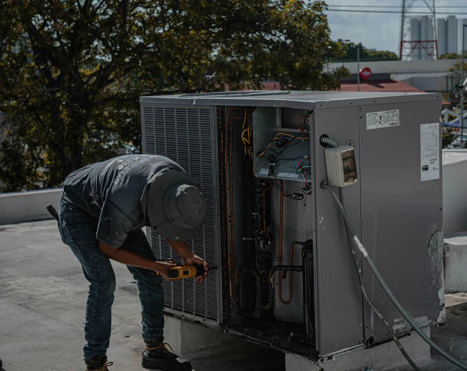 South Florida HVAC tech diagnosing a rooftop AC condensing unit with a multimeter, the kind of measurement-based check that should precede any compressor replacement quote