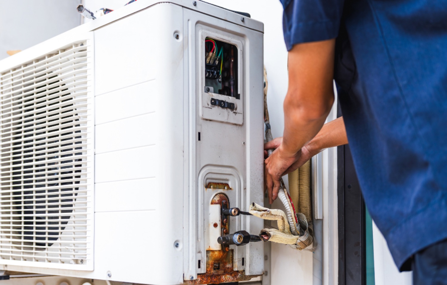Hand holding a remote control pointed at a wall-mounted AC unit
