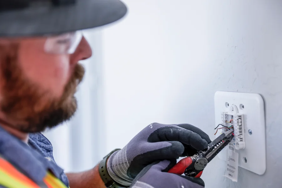 Licensed HVAC technician installing smart thermostat wiring